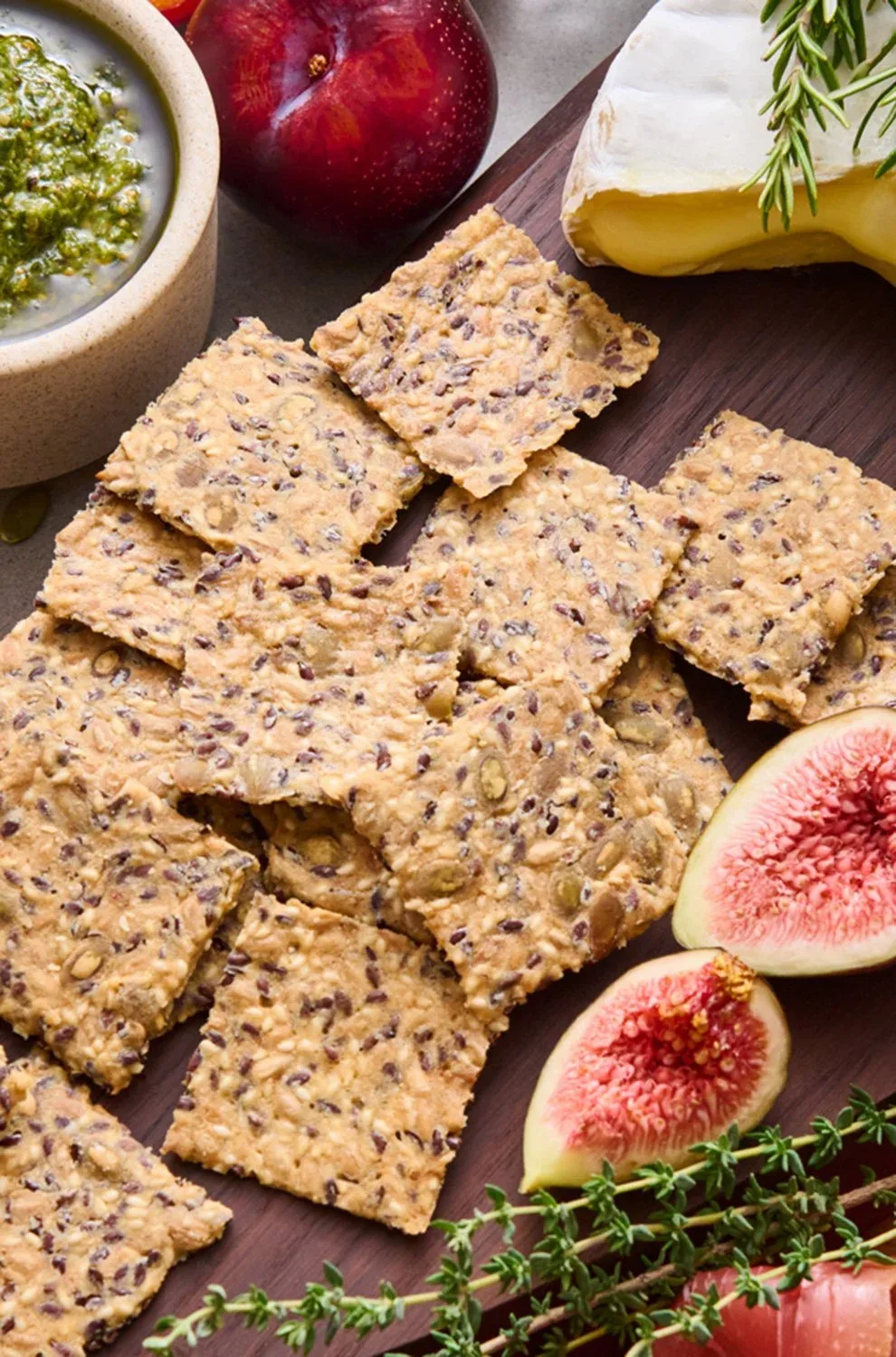 A wooden cheese board with cheeses, dips, fresh figs and Mette is Baking crackers