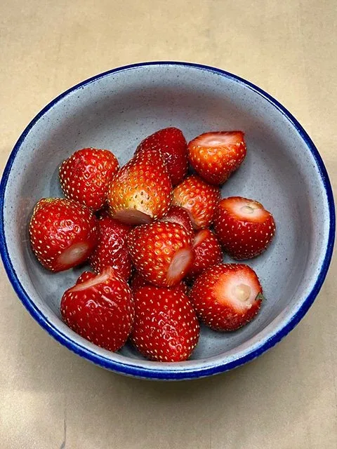 A blue bowl filled with hulled strawberries