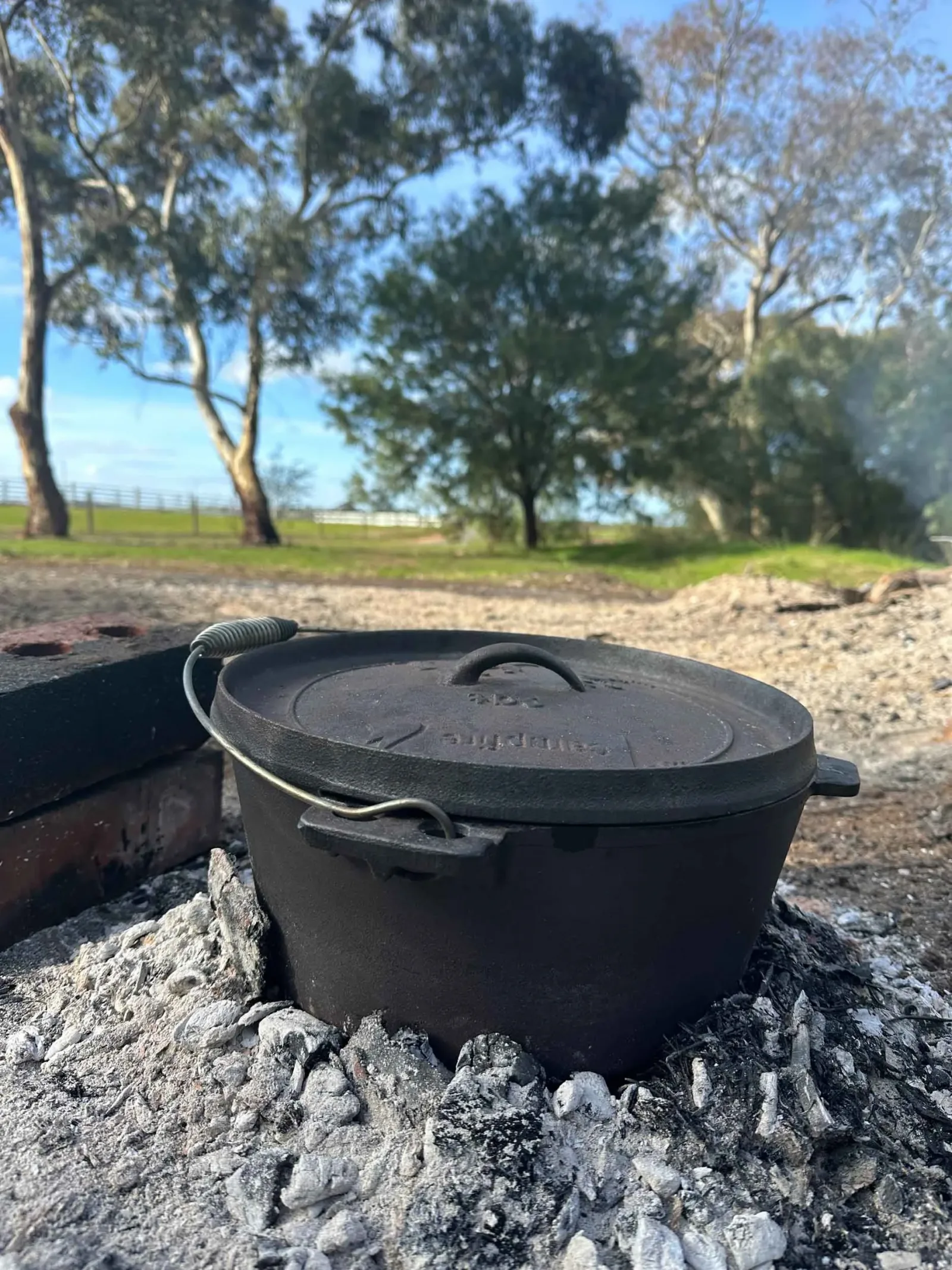 The camp oven sitting on top of hot coals, cooking the ribeye out in the Australian bush