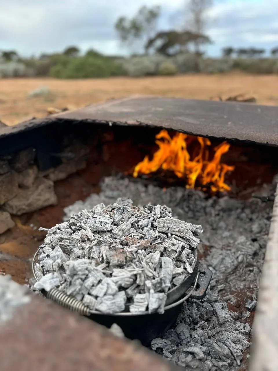 A camp oven cooking cheese bread rolls