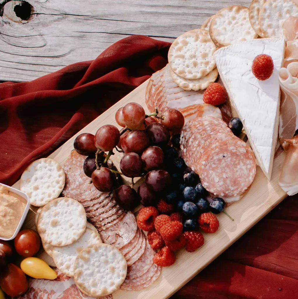Round table water crackers arranged on a board with cheese and accompaniments